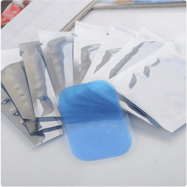 Packets of replacement gel pads for the EMS stimulator, laid out with one gel pad exposed
