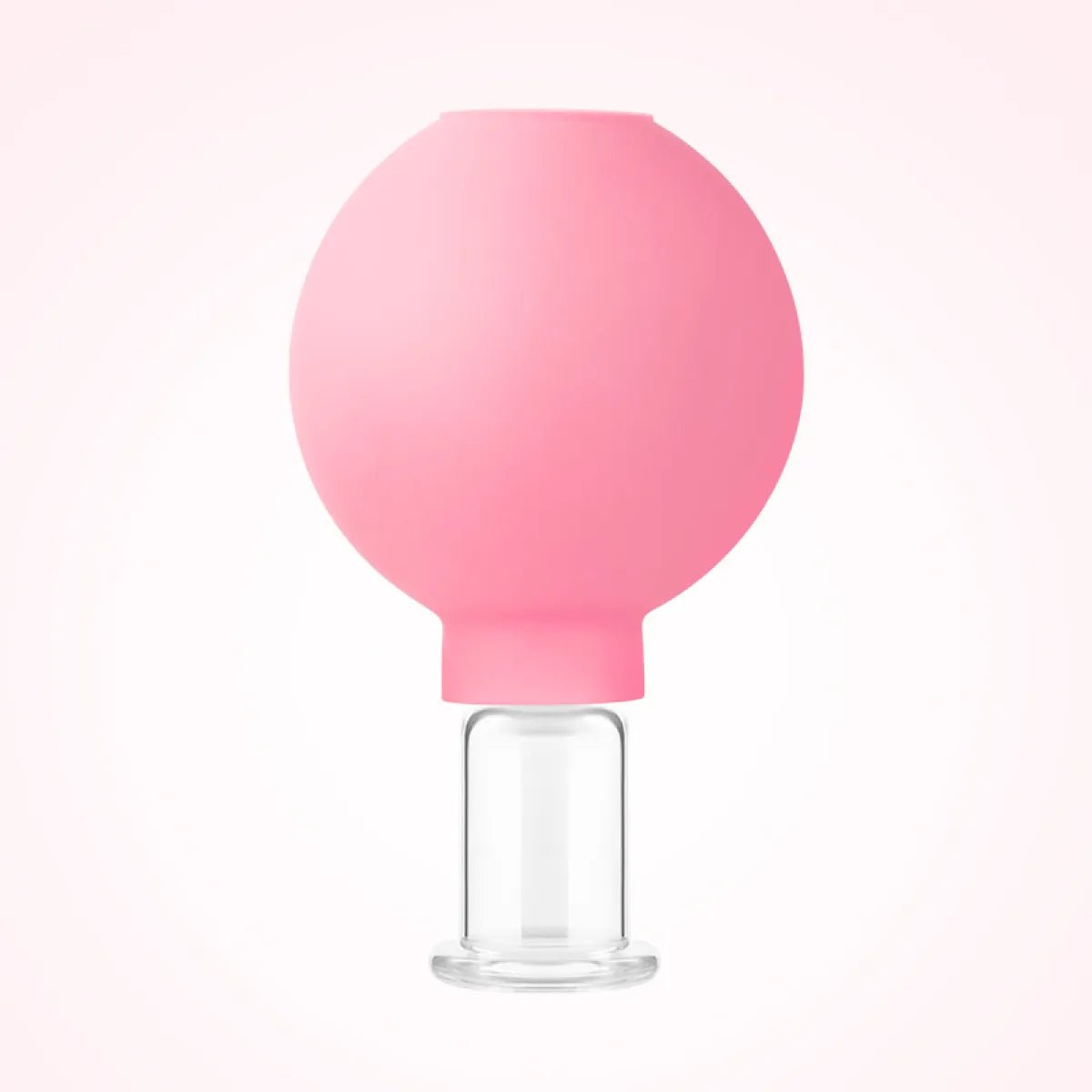 Pink silicone cupping tool with glass base, standing upright